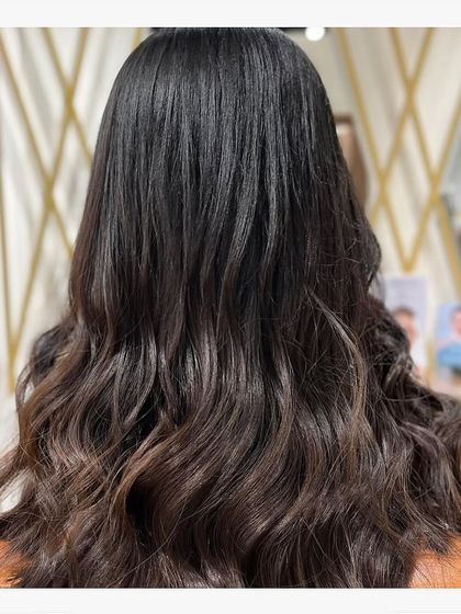 A back view of the long, dark hair with soft waves, highlighting the texture and healthy gloss of the hair.