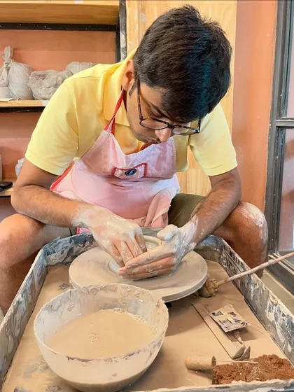 A young man fully engaged in shaping his creation on the wheel, experiencing the magic of pottery firsthand.