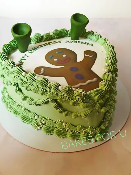 A fun, heart-shaped vintage cake with a Shrek-themed twist. The design features the Gingerbread Man and Shrek's iconic ears, all in a vibrant green.