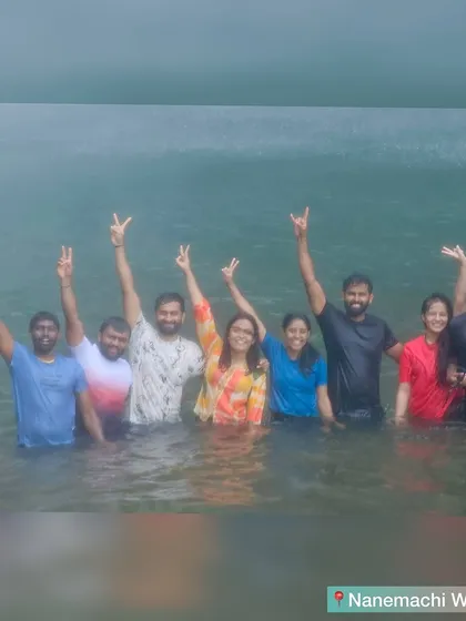 The whole group with their hands up, celebrating in the waters of Nanemachi waterfall.