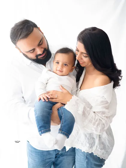 A beautiful family of three. The parents look at their baby with so much adoration, creating a classic and loving family portrait.
