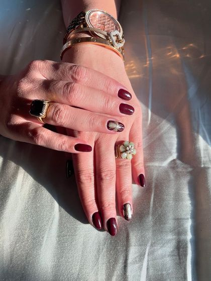 A sophisticated dark red set with a cat-eye effect on one nail and a gold accent. This work by a student shows their ability to create elegant and trendy looks.