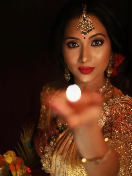 A magical Deepavali shot, with the focus on the light from the diya. Her makeup is kept classic with a red lip and defined eyes, creating a timeless festive glow.