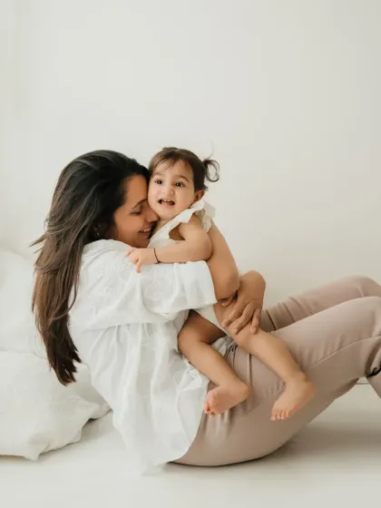 A mother and daughter share a playful moment on the floor. This candid photo is full of laughter and love.