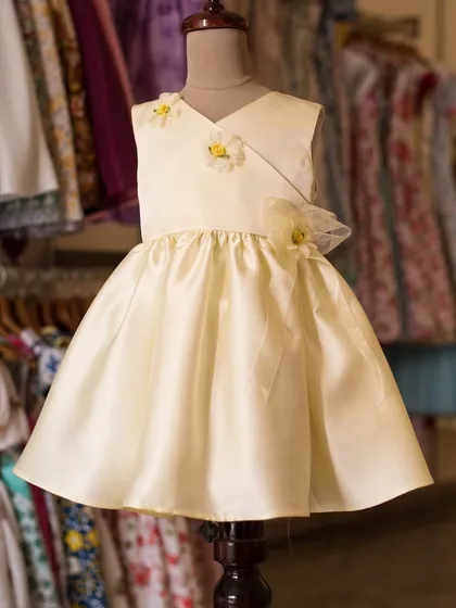 A simple and elegant buttercup yellow dress. The design is elevated by delicate handmade flower details on the bodice, adding a touch of bespoke charm.