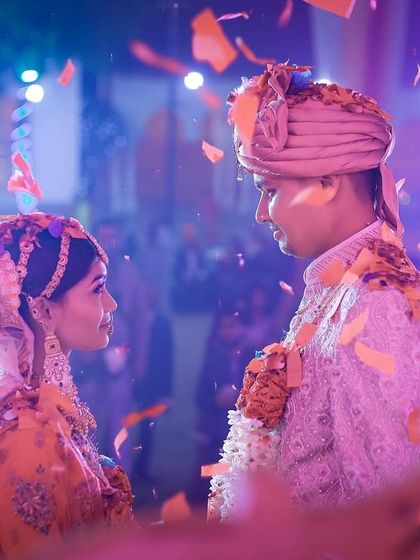 A beautiful moment during the Jaimala ceremony, with confetti falling around the couple. The lighting and emotion make this a powerful shot.