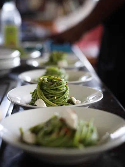 Plating a line of spinach pesto spaghetti. Consistency and attention to detail are drilled into our students for professional service.