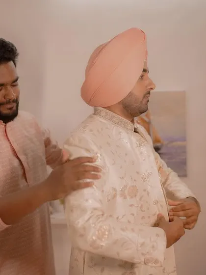 A helping hand from a brother or friend. A candid moment of the groom getting ready, showcasing the support and love surrounding him.