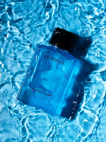 A fresh and clean shot of a blue perfume bottle submerged in rippling water. This is a classic way to visually communicate a fresh, aquatic scent.