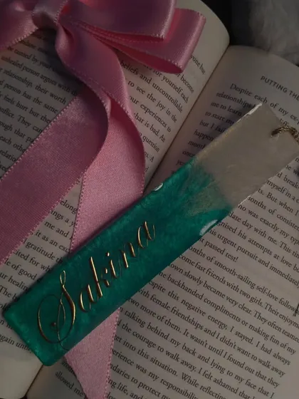 This custom bookmark for 'Sakina' is styled with a book and ribbon. The deep green and gold combination is very elegant.
