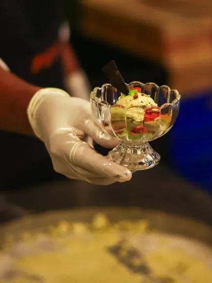 A hand holds a crystal glass of our beautifully prepared ice cream dessert.