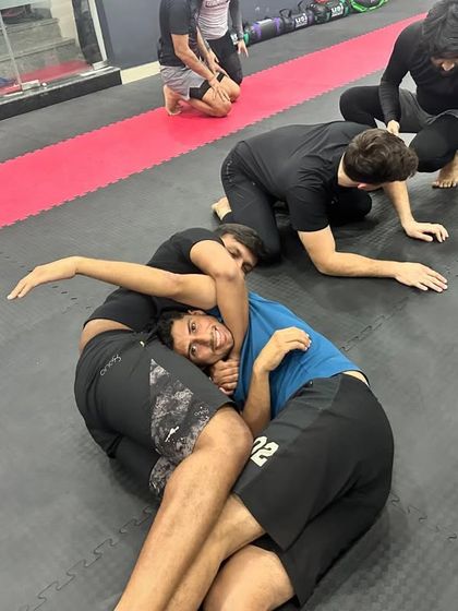 Even during intense grappling rolls, the spirit of our community shines through. Here, students are seen smiling while practicing positioning and control on the mat.