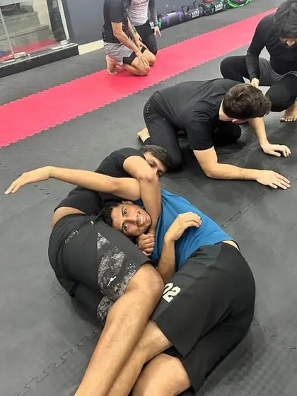 Even during intense grappling rolls, the spirit of our community shines through. Here, students are seen smiling while practicing positioning and control on the mat.