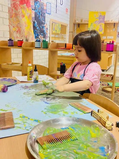 This child uses a comb to create textures in the paint, a wonderful example of using unconventional tools in art. This process-led exploration encourages her to think outside the box and discover new ways of creating.