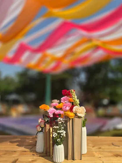 The book-and-flower centerpiece, set against the backdrop of the colorful draped ceiling of the 'Artistic Atelier' Haldi.