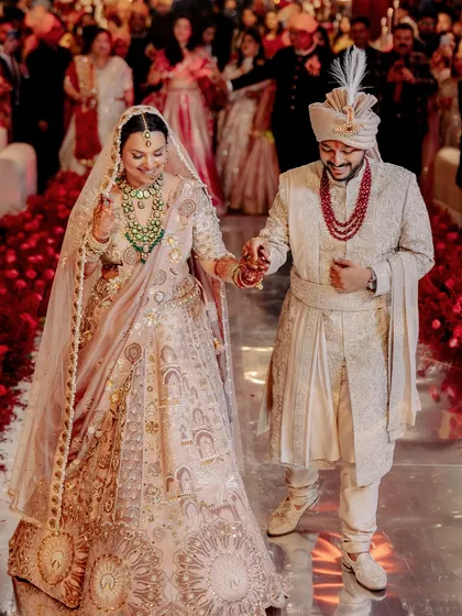 The bride and groom walking down the aisle together, hand in hand, on a path of red rose petals.