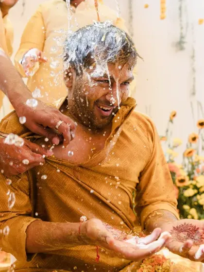 The groom gets doused with milk or lassi, another fun and messy part of the Haldi rituals. His expression of shock and laughter says it all.
