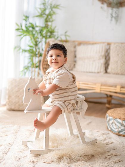 A little boy enjoying a ride on a classic white rocking horse. Sitter sessions are perfect for capturing these playful moments and new skills.