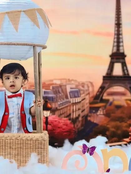 A handsome little gentleman in a vest and bow tie, posing in a hot air balloon basket against our beautiful Parisian skyline backdrop.