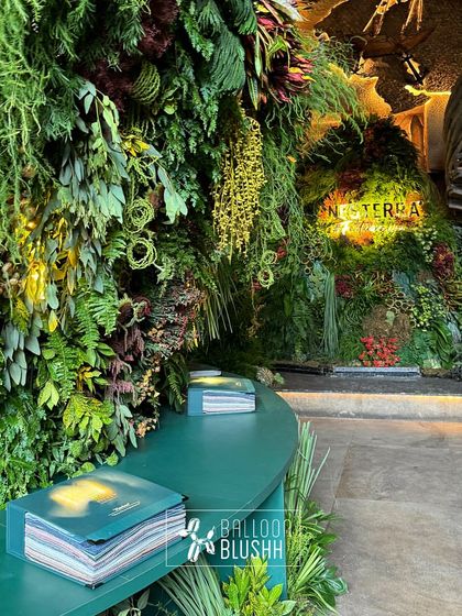 A seating area at the Nesterra event, set against a backdrop of a floor-to-ceiling vertical garden. The design seamlessly integrates the brand's home decor products with a natural, biophilic environment.