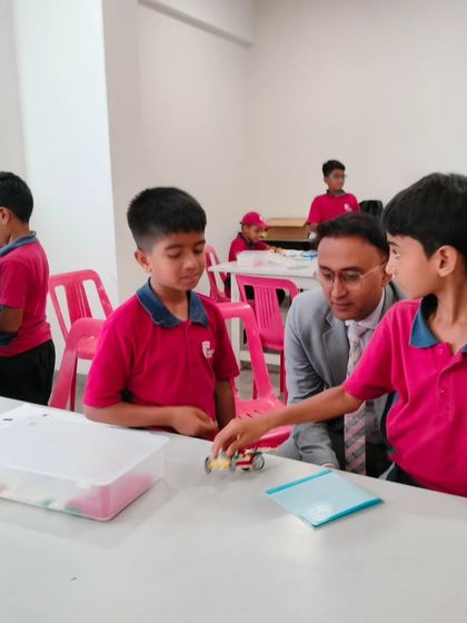 A parent from Vidyashilp Academy listens intently as his son explains the functionality of the car he built and programmed.