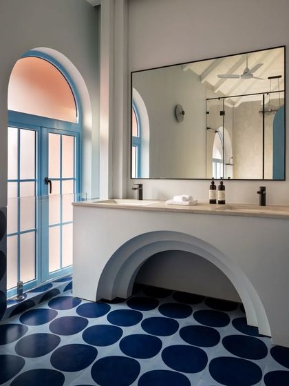 In this Goan villa bathroom, I used arches and playful circular floor tiles to create a whimsical yet sophisticated space. The frosted glass in the arched window allows for privacy while flooding the room with natural light, maintaining the home's airy, open concept.