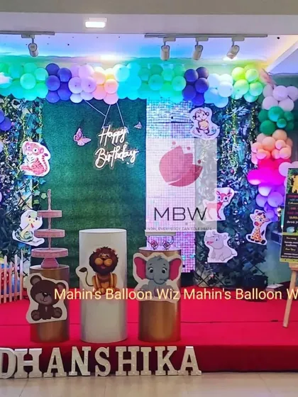 This full view of the woodland animal party shows the complete stage design, including the "Happy Birthday" neon sign and the personalized milestone board on an easel.