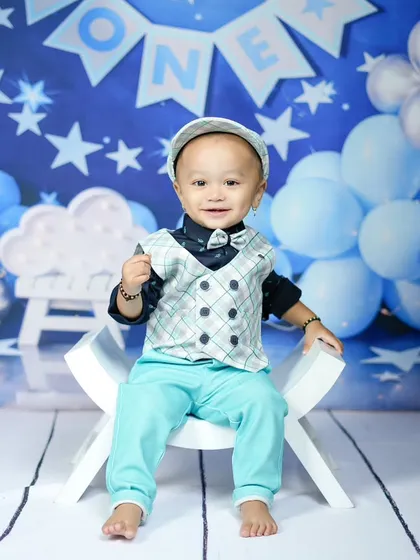 Dressed up and ready to celebrate his first birthday. The blue and silver star-themed backdrop adds a touch of magic to the occasion.