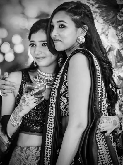 A moment of sisterhood. This black and white photo captures two sisters sharing a quiet moment during the wedding festivities, their bond evident in their close embrace.