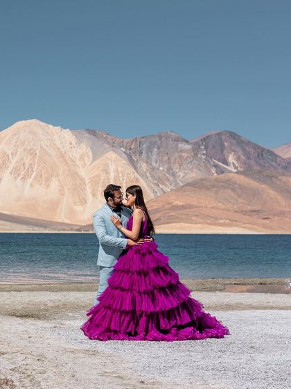 An intimate moment of connection amidst the grand landscape of Leh. The contrast between the soft blue suit and the vibrant purple gown adds a touch of high fashion to this stunning natural setting.