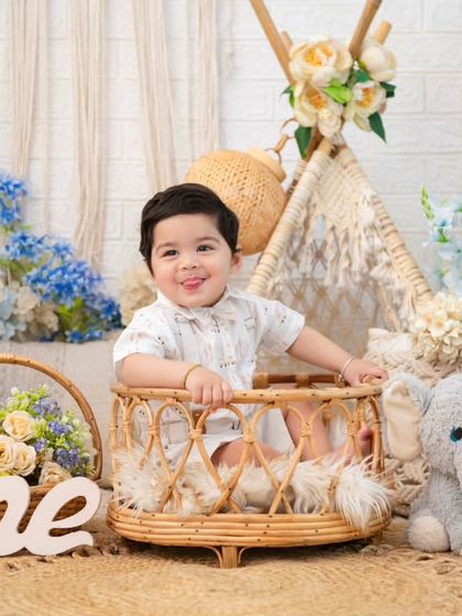 A happy boy in his boho first birthday setup. The wooden 'One' sign and the teepee are popular props that add a special touch to these sessions.