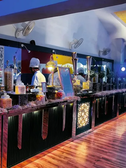 A full view of a rustic-themed buffet counter. The design incorporates natural textures and warm lighting to create a welcoming and stylish food station for a festive gathering.