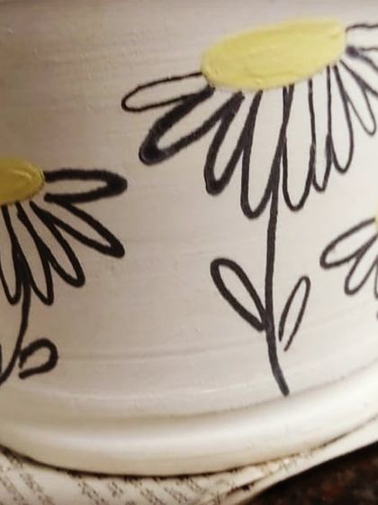 A peek at a piece being decorated behind the studio doors. This hand-painted daisy mug shows how you can add a personal touch to your pottery.