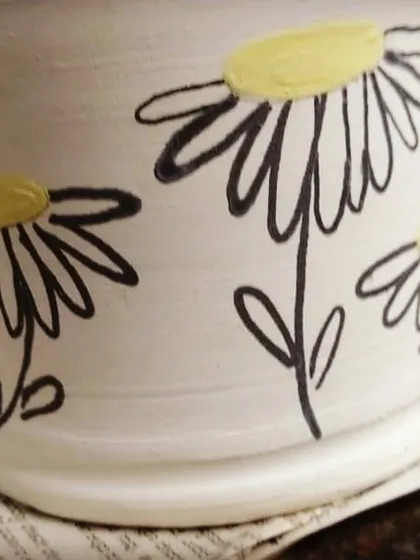 A peek behind the studio doors at a piece being painted. After a pot is created on the wheel and fired once, you can add your own personality with underglaze painting.
