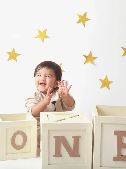 A star is one! This little boy's joyful expression, surrounded by golden stars, perfectly captures the excitement of his first birthday.
