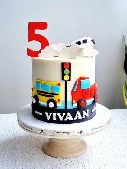 A clean shot of the vehicle-themed cake, showing the 2D fondant bus and truck.
