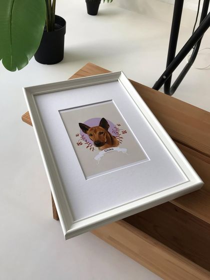 Another view of the framed Chiku portrait, showing how it looks as a finished piece on a wooden surface in my studio.