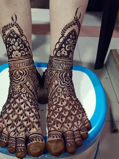 This foot design features a classic jaal (net) pattern across the toes and a beautiful floral band around the ankle. It's a timeless choice that complements any bridal hand mehendi.