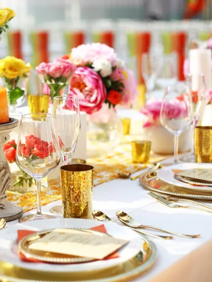 A stunning tablescape with gold accents and bright floral arrangements, showcasing a luxurious and celebratory mood. Every detail is considered to create a great, not just good, event.