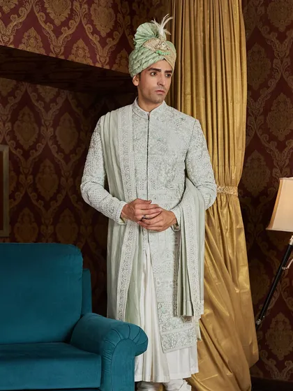 The full-length view shows the impeccable tailoring and graceful silhouette of the light green sherwani. It's designed to be as comfortable as it is elegant.
