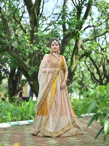 A beautiful shot of the mustard yellow lehenga, with the sheer dupatta draped elegantly across the front.