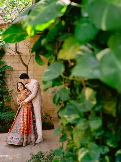 A sweet, candid moment of the couple tucked away amidst lush green leaves during their Mehendi ceremony.