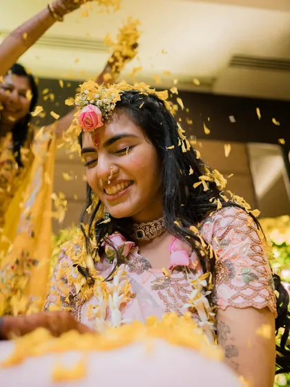 A sweet, candid moment of a bride smiling as she gets turmeric applied. Her genuine happiness is what makes this photo so beautiful.