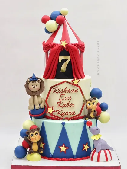 The full view of the colorful circus cake, with a tent topper, a lion, monkeys, and a seal.