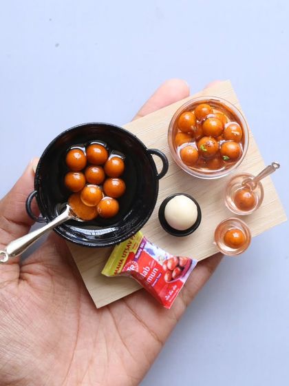 A tray of miniature gulab jamuns, complete with a tiny packet of the mix.