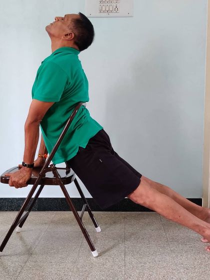 Urdhva Mukha Shvanasana (Upward-Facing Dog) with hands on a chair. This elevates the torso, allowing for a deeper opening in the chest and shoulders while reducing pressure on the wrists.