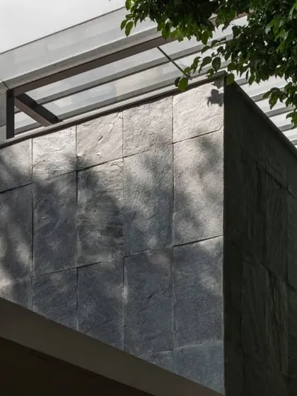 A close-up detail of the dark slate tile cladding used on the exterior. This durable and locally sourced Indian stone provides a rich texture that contrasts with the smooth white walls.
