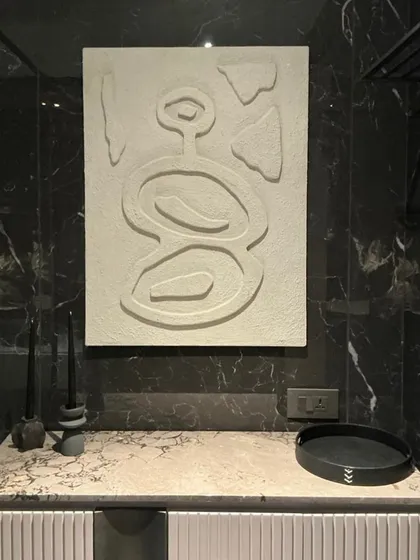 The finished white textured artwork installed in a bathroom, adding a touch of organic, spa-like calm to the modern space with its dark marble walls.