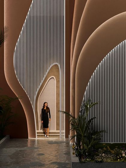 The entrance to the "Water & Wind" residence is a dramatic, cave-like opening within the flowing facade, inviting you into the home's unique world.