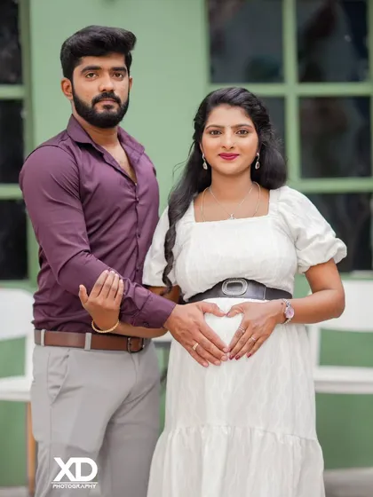 A loving couple's portrait with their hands forming a heart on the baby bump.